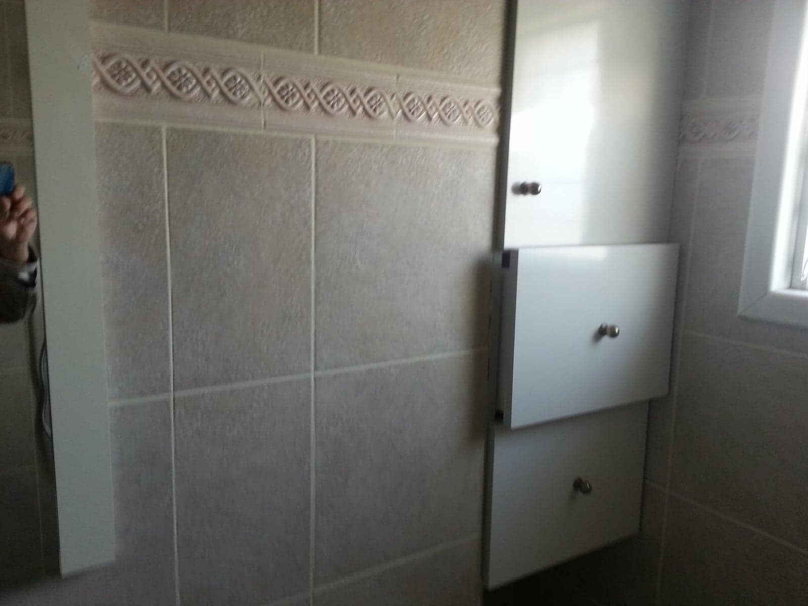ארון אמבטיה תלוי ליד חלון בחדר רחצה משופץ