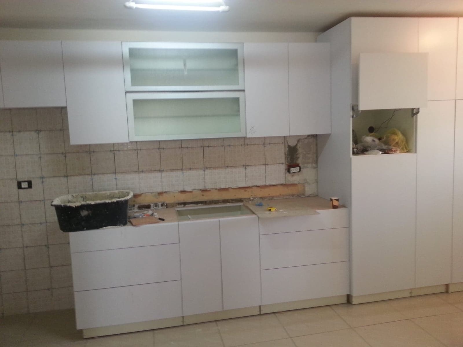 מטבח לבן חדש בהתקנה — ארונות תחתונים ועליונים