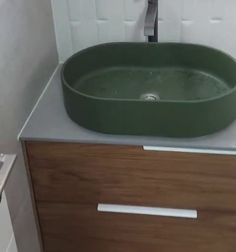 כיור ירוק על ארון אמבטיה מעץ בחדר רחצה משופץ