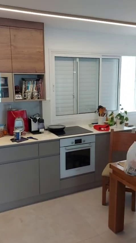 מטבח אפור עם ארונות עליונים מעץ אחרי שיפוץ