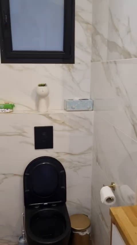 אסלה תלויה שחורה וחיפוי בדמוי שיש בשירותי אורחים